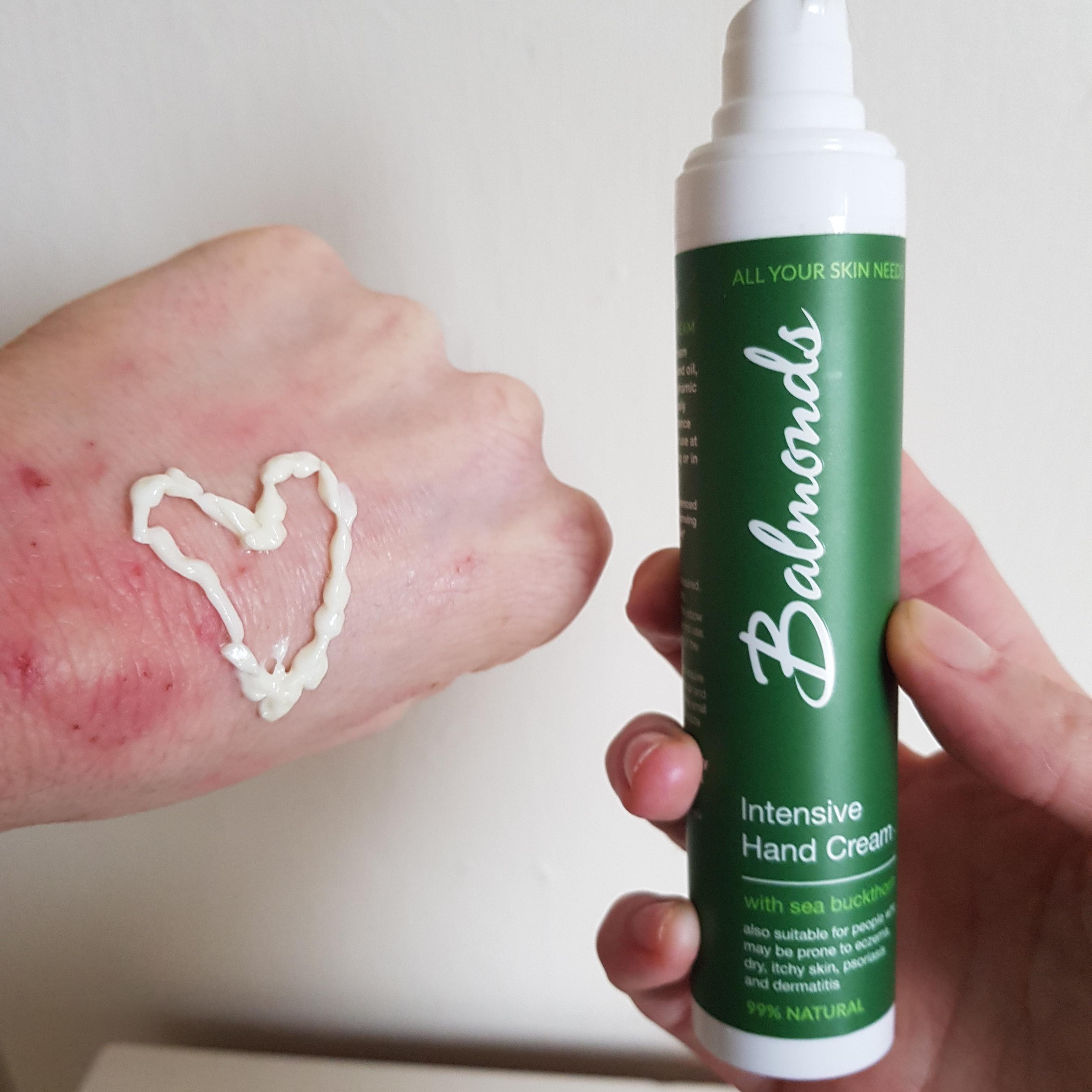 Balmonds hand cream tube next to hand with cream on in a heart shape